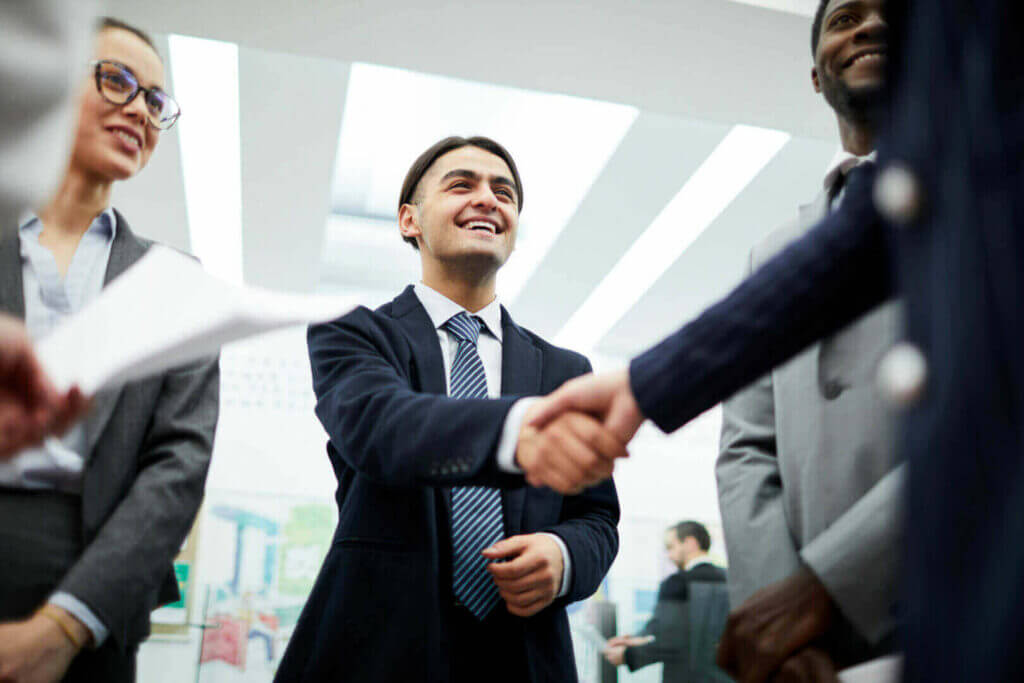 Business professionals shaking hands in formal attire, symbolizing successful partnership and networking.