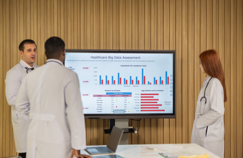 Team of doctors analyzing healthcare big data for cost-effective solutions on digital screen in modern office.
